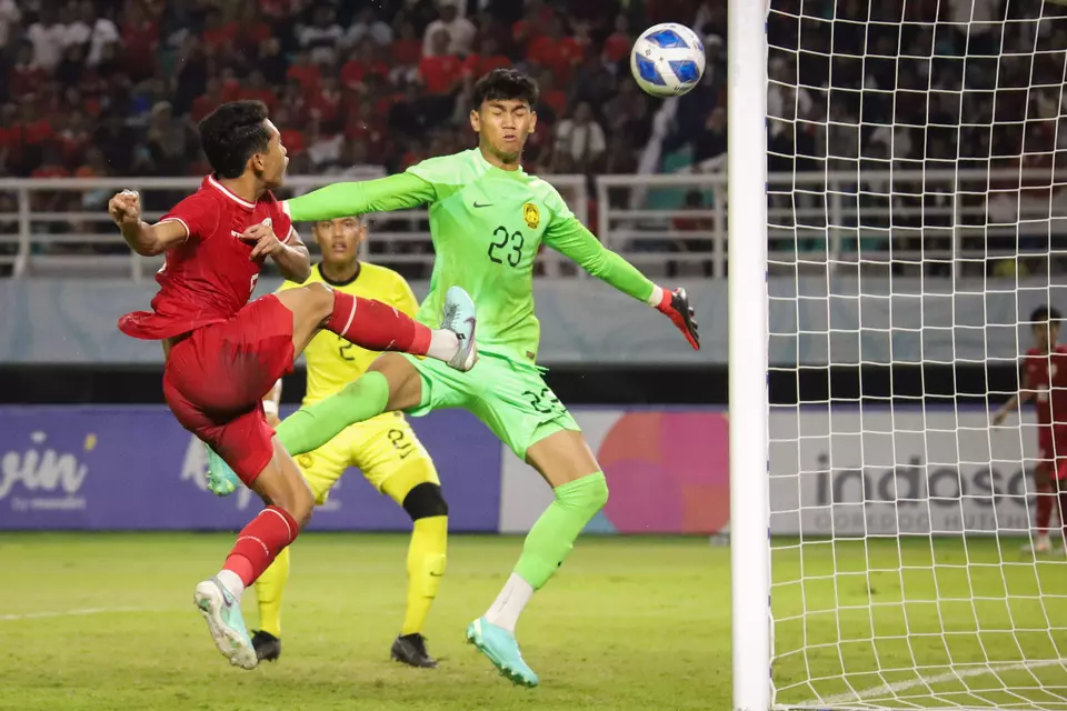 Bek Timnas Indonesia U-19 Muhammad Alfharezzi Buffon (kiri) berusaha menjebol gawang Malaysia yang dijaga Muhammad Hazig Aiman bin Mohd Esa (kanan) dalam pertandingan semifinal Piala ASEAN U-19 Boys Championship atau AFF U-19 di Stadion Gelora Bung Tomo, Surabaya, Jawa Timur, Sabtu, 27 Juli 2024.